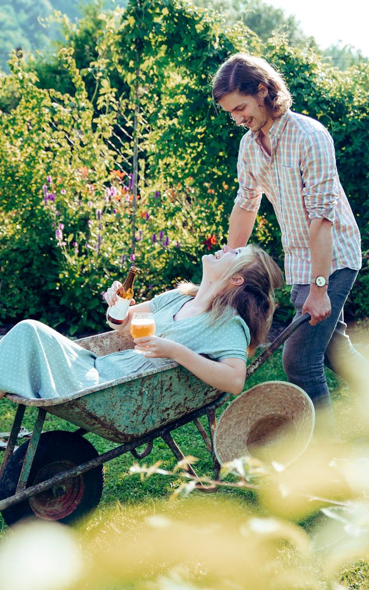 Herbsturlaub in Bad Gleichenberg - Frau sitzt mit Bier in der Schiebetruhe und wird von Herr durch den Garten geschoben