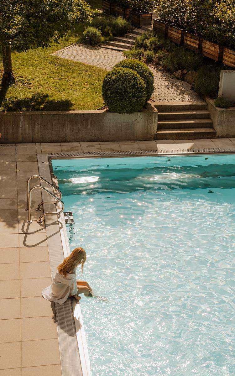 Frau sitzt am Pool in der Abendsonne im Legenstein