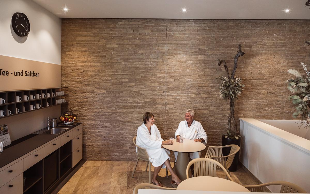 Mann und Frau sitzen auf Stühlen mit Tisch in der Tee- und Saftbar im Wellnessbereich Vulkanium - Winterurlaub in Bad Gleichenberg