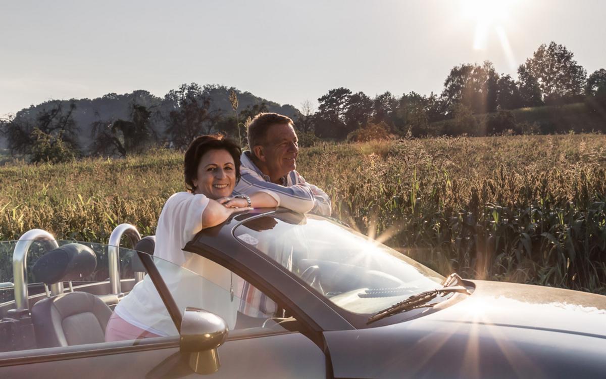Mann und Frau stehen mit Cabrio im auf einer Forststraße zwischen Maisfelder und genießen die Sommersonne - Sommerurlaub in Bad Gleichenberg