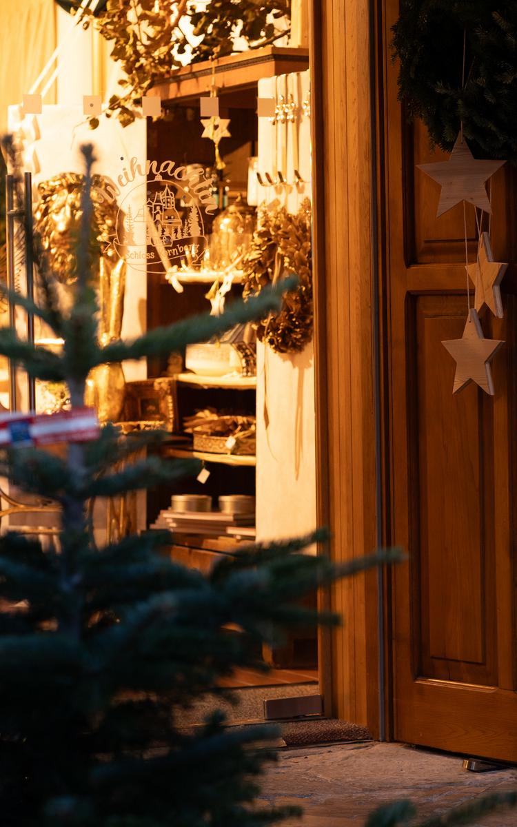weihnachtliche wegweiser wie tannenbaum und holzsterne führen zur eingangstuer des adventmarktes auf schloss kornberg im thermen- und vulkanland steiermark, nahe des vulkanlandhotel legenstein