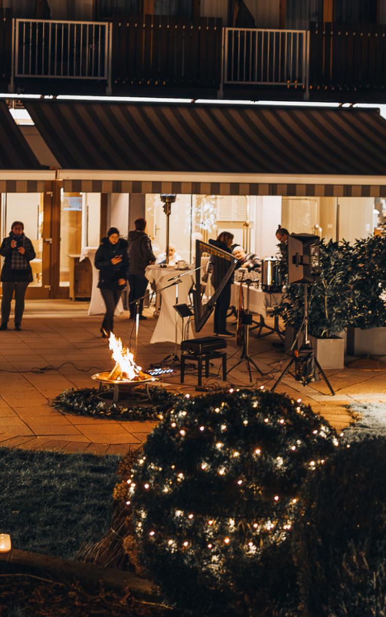 Gäste stehen draußen im Garten & genießen die Advent-Einstimmung in der Vorweihnachtszeit bei Glühwein & Lebkuchen im Vulkanlandhotel Legenstein