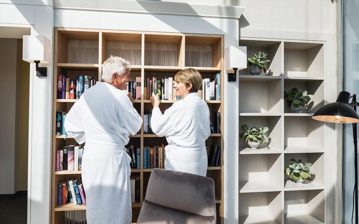 Frau und Mann schmoekern im Bücherregal in der Bücherwurmlounge - Genuss und Wandern im Vulkanland - Preise Vulkanlandhotel Legenstein