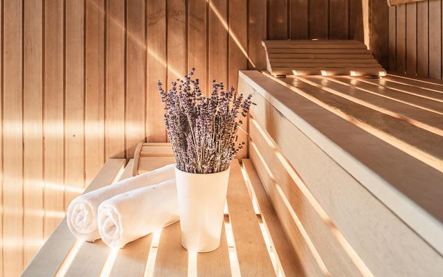 eine vase mit einem lavendelstrauss steht in der bio-kräuter-sauna neben zwei handtuchrollen