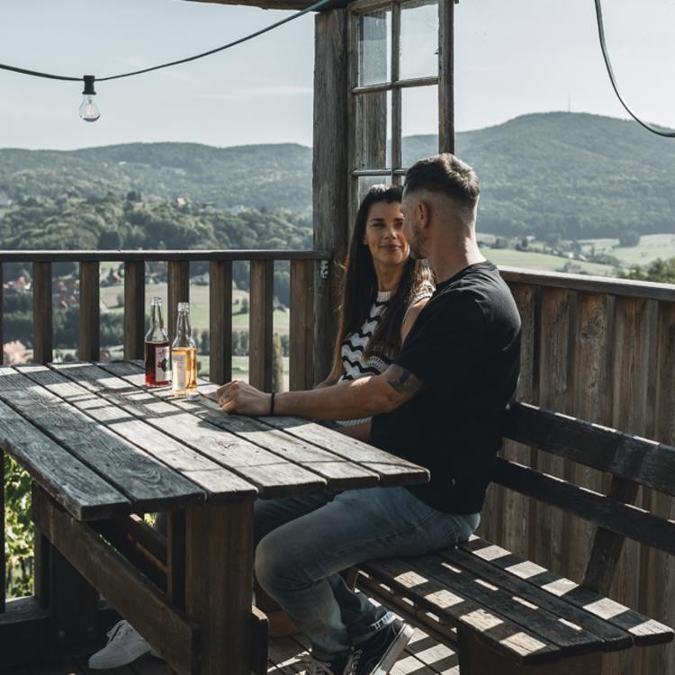 Tochter und Vater stoßen mit Weingläsern im Weingarten an, die Sonne schein, sie freuen sich - Kulinarik, Wandern und Wein im Thermen- und Vulkanland Steiermark - Preise im Vulkanlandhotel Legenstein
