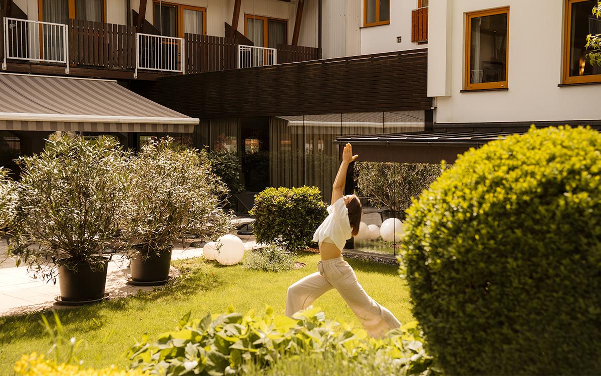 Frau praktiziert Yoga in der Gartenlandschaft im Legenstein
