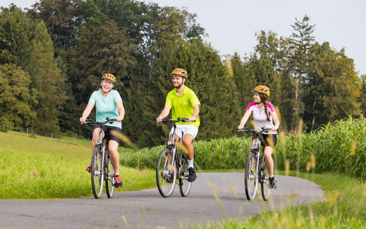 Zwei Frauen und ein Mann fahren mit dem Fahrrad bzw. mit dem E-Bike durch Bad Gleichenberg - E-Biken im Vulkanland - Preise Vulkanlandhotel Legenstein