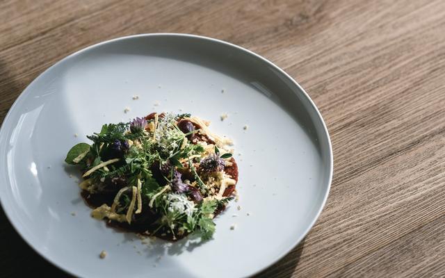 hirsch-carpaccio, schön angerichtet auf einem teller, mit blüten und kräuter im herbsturlaub im vulkanlandhotel legenstein in bad gleichenberg