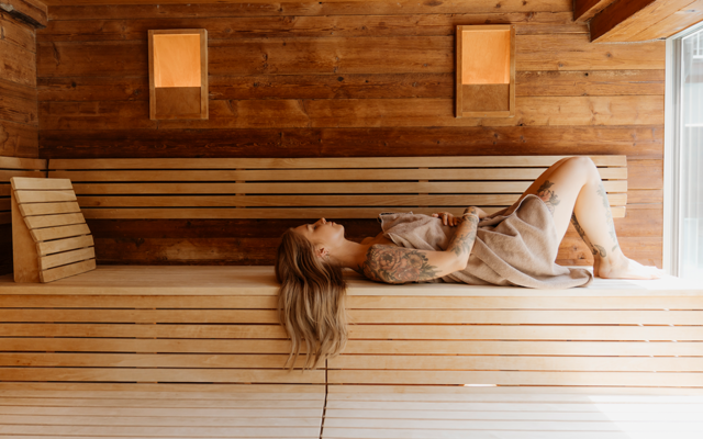 Eine Frau entspannt in der finnischen Sauna des Vulkanlandhotels Legenstein.