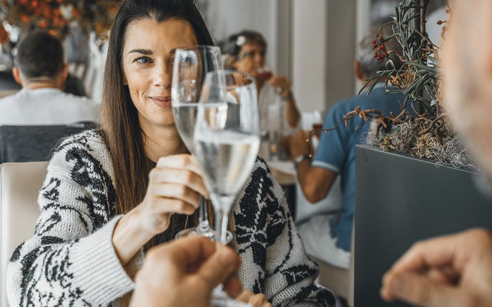 ein pärchen frühstückt im urlaub im vulkanlandhotel legenstein im restaurant feuergott und stoßt auf erholsame tage im thermen- und vulkanland steiermark mit einem glas sekt an