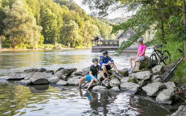 radfahrer sitzen vor der murecker schiffsmühle und genießen eine abkühlen an der mur beim radurlaub im vulkanlandhotel legenstein in bad gleichenberg