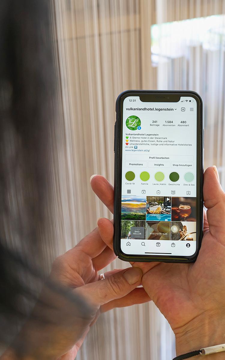 Kostenfreies Wlan im Hotel - eine Frau hält ihr Handy mit der Vulkanlandhotel Legenstein-Instagram-Seite geöffnet hoch