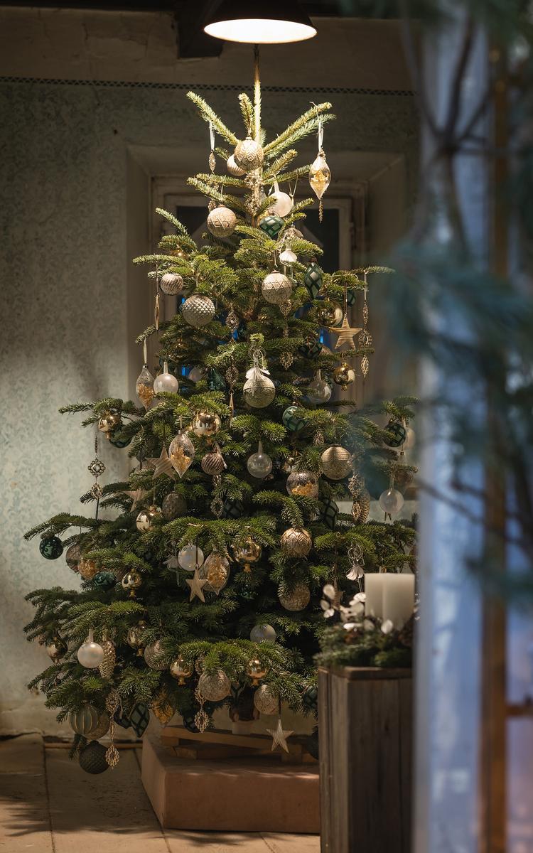 bei der weihnachtsausstellung von sieglinde blumenhandwerk steht ein großer tannenbaum, geschmückt mit glitzernden kugeln