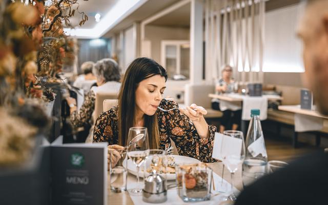 ein paerchen sitzt im restaurant feuergott und die frau geniesst das wunderbare menü mit geschlossenen augen