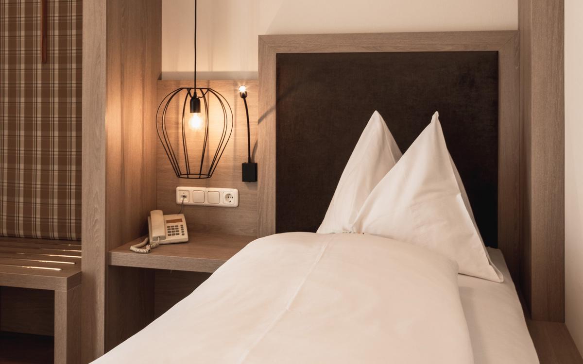 Bett mit Nachttisch und Lampe im Einbettzimmer Weinberg - Preise im Vulkanlandhotel Legenstein in Bad Gleichenberg