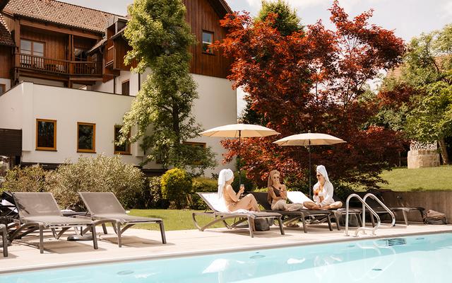 Drei Frauen genießen die Sonne am Pool im Legenstein