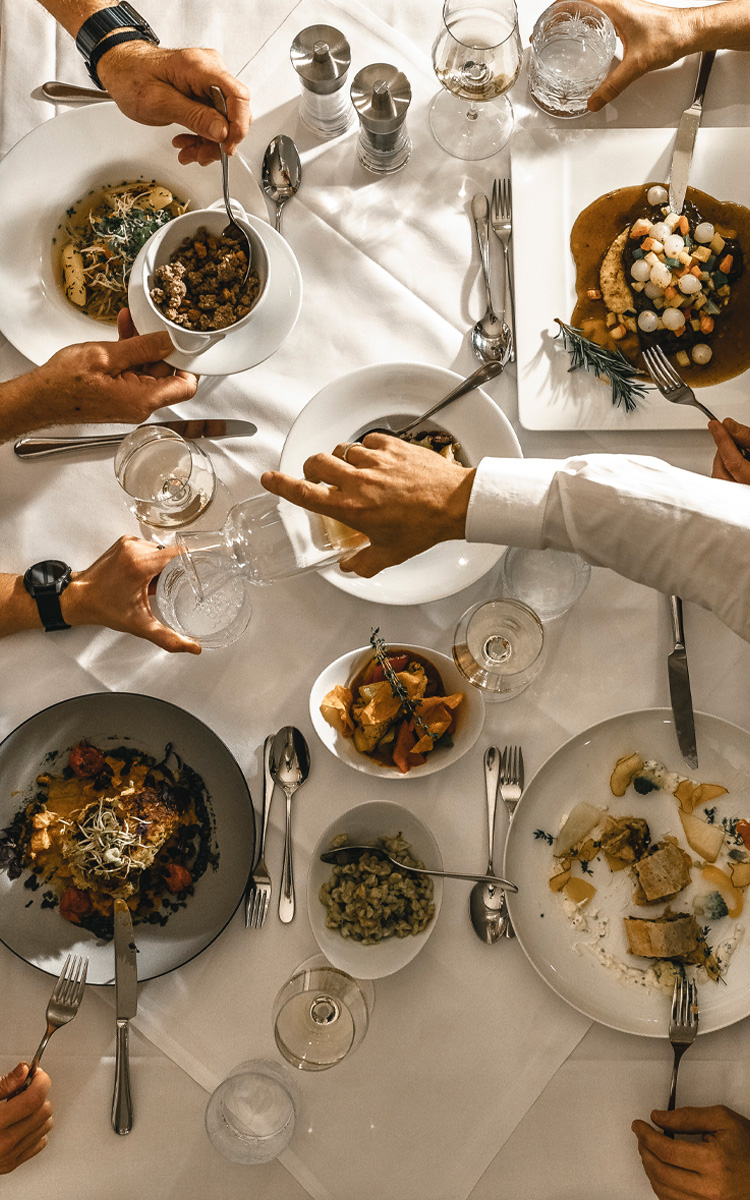 freunde sitzen am tisch und genießen das abendmenü - den reichlich gedeckten tisch im restaurant feuergott im vulkanlandhotel legenstein in bad gleichenberg in der südoststeiermark