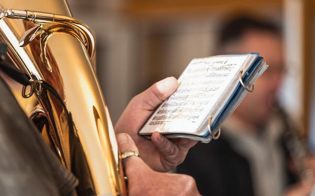 Ein Blasmusiker hält die Noten in der Hand und spielt am Tenorhorn